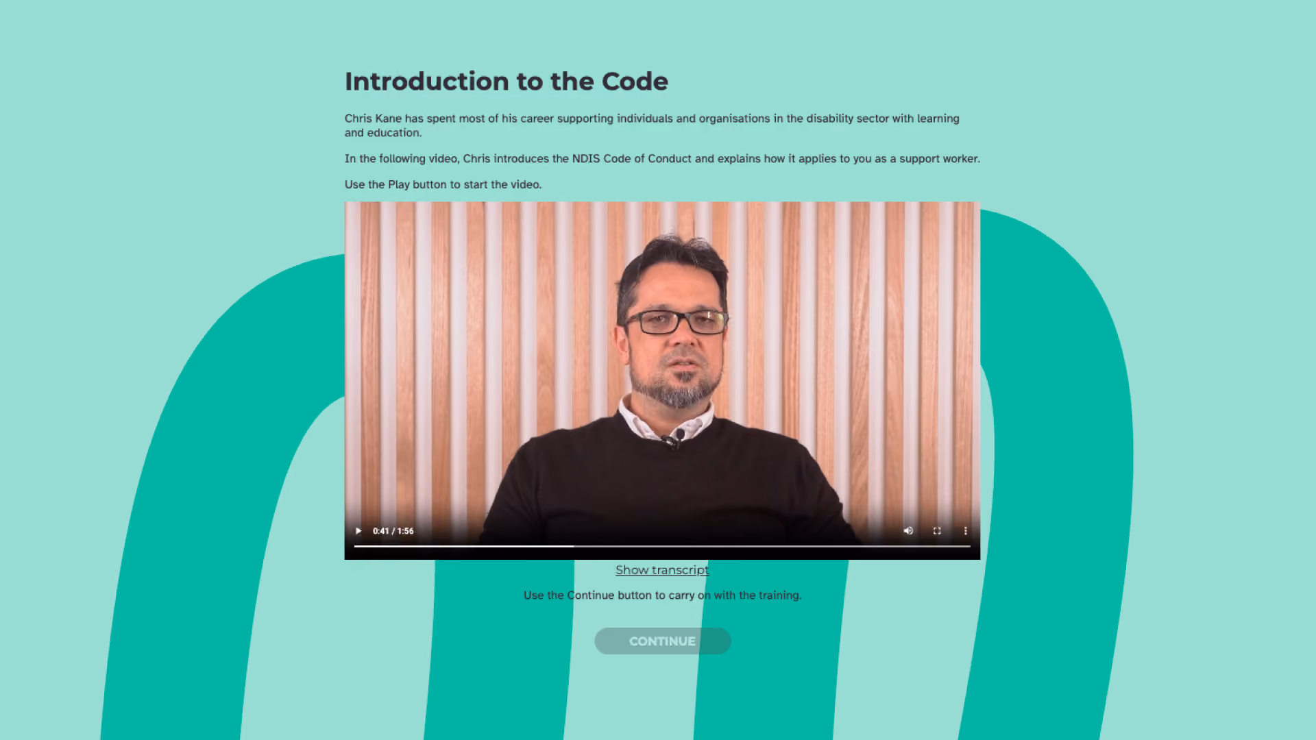 A man in glasses speaks to camera against a timber slat wall, in the "Introduction to the Code" video presented by Chris Kane.