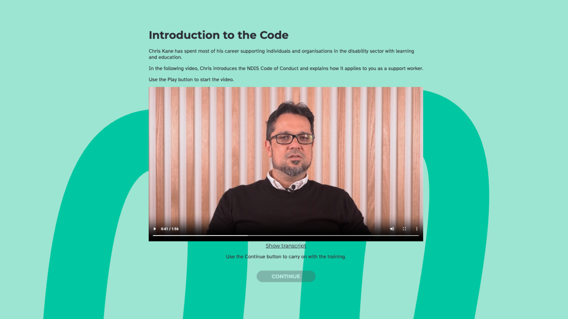A man in glasses speaks to camera against a timber slat wall, in the "Introduction to the Code" video presented by Chris Kane.