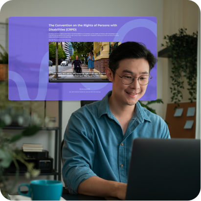 A man smiling while using a laptop at home, with a purple online training screen about the Convention on the Rights of Persons with Disabilities displayed behind him.