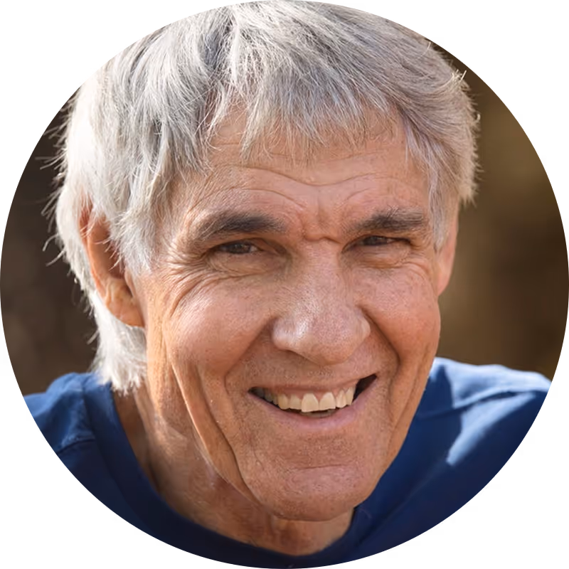 Headshot of a man with silver-gray hair and a warm smile, wearing a blue shirt or jacket