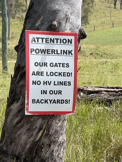Rural landowner's sign nailed to a gum tree warning Powerlink that gates are locked and opposing high voltage transmission lines on their property.