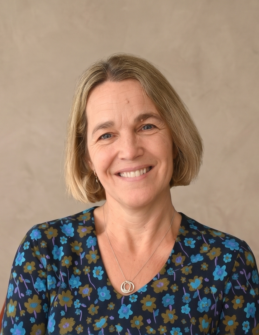Smiling woman with short blonde hair wearing a green floral top and a silver necklace.