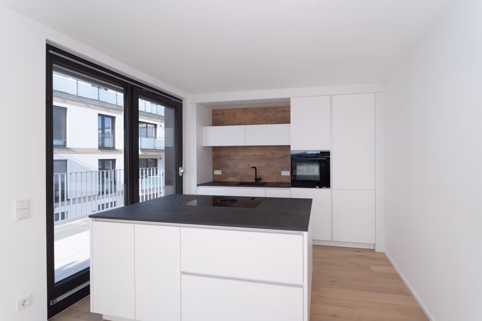 Immobilienfotografie – offene Küche mit eleganter Linienführung, dunkler Arbeitsplatte und natürlichem Lichteinfall