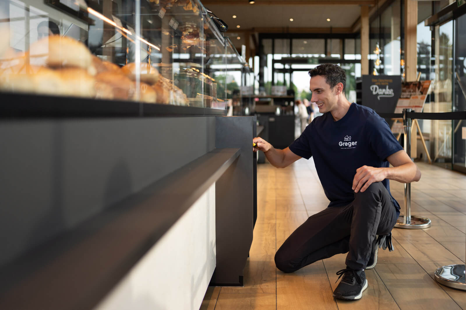 Corporate Fotograf begleitet einen Greger Haus und Garten Techniker bei der Arbeit in einer Bäckerei und zeigt präzise Handwerksarbeit im Alltag.