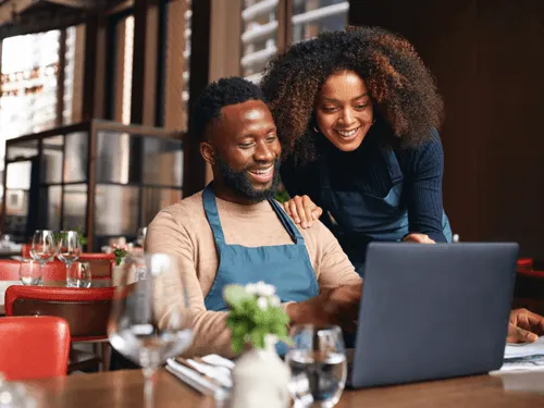 Two people looking at a computer and smiling.
