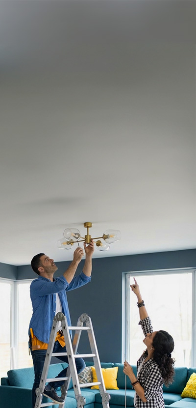 Husband hanging up a light with wife