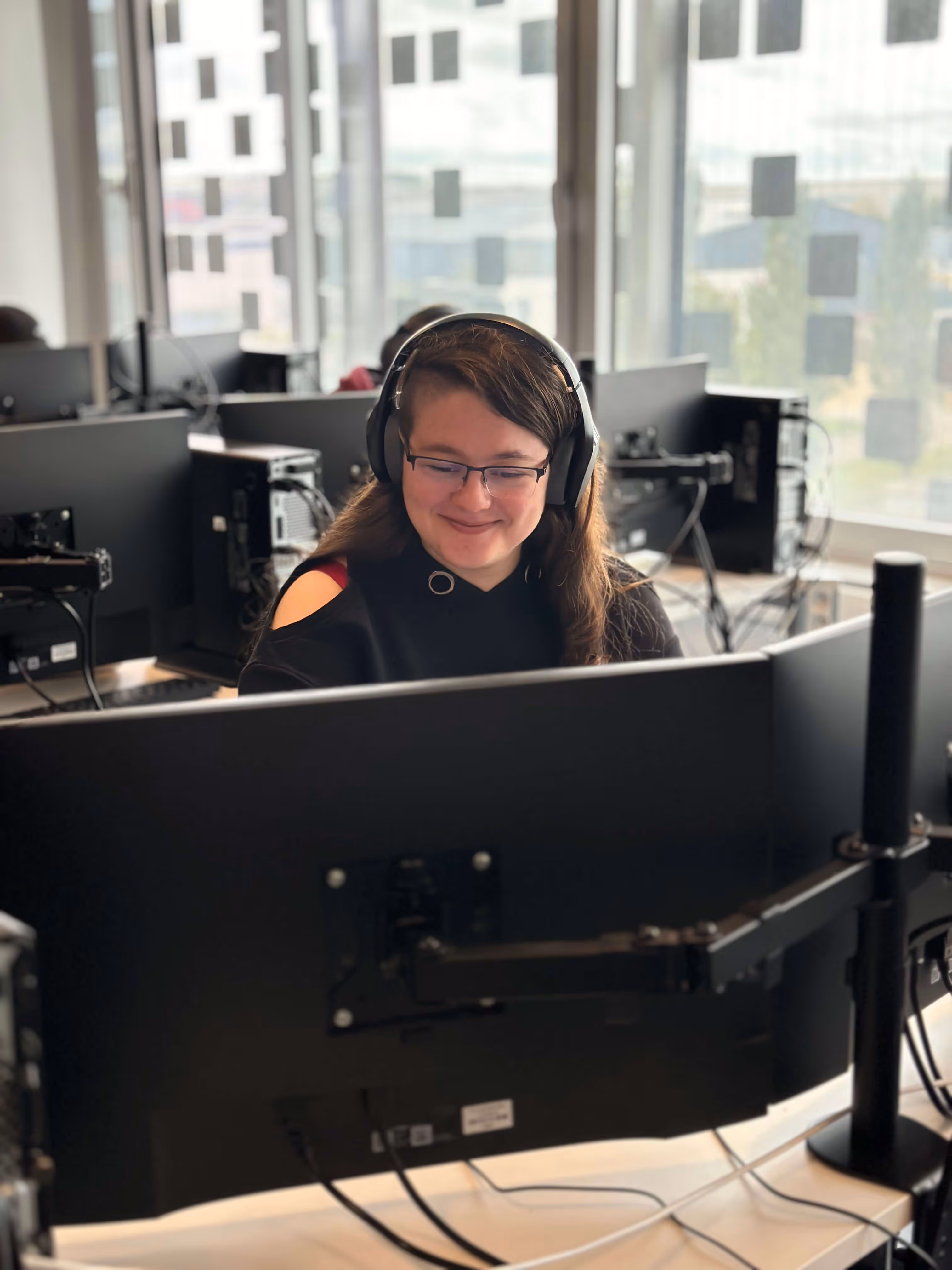 A happy female behin a big desktop screen, working