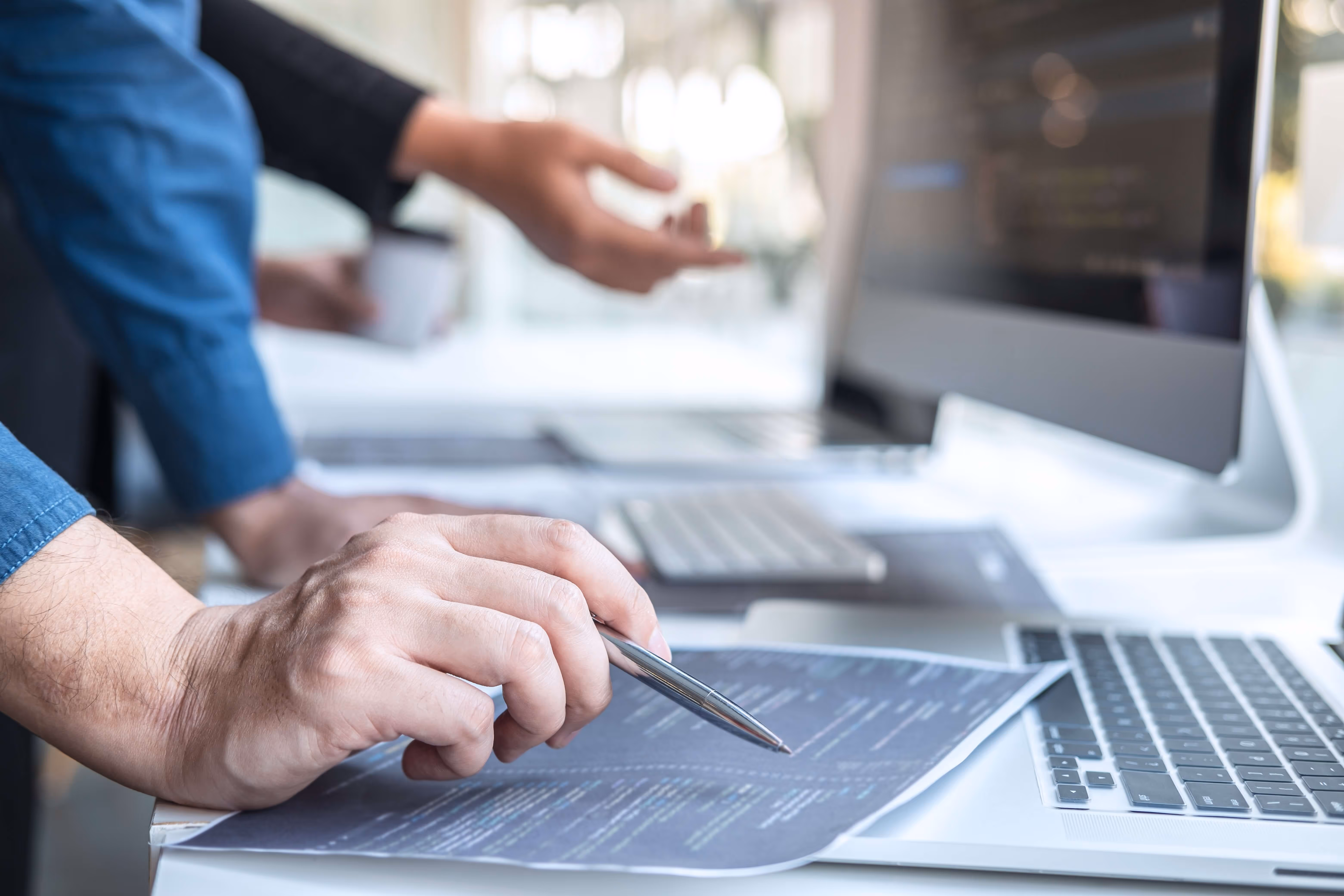 Professional developer holding a pen in front of a computer