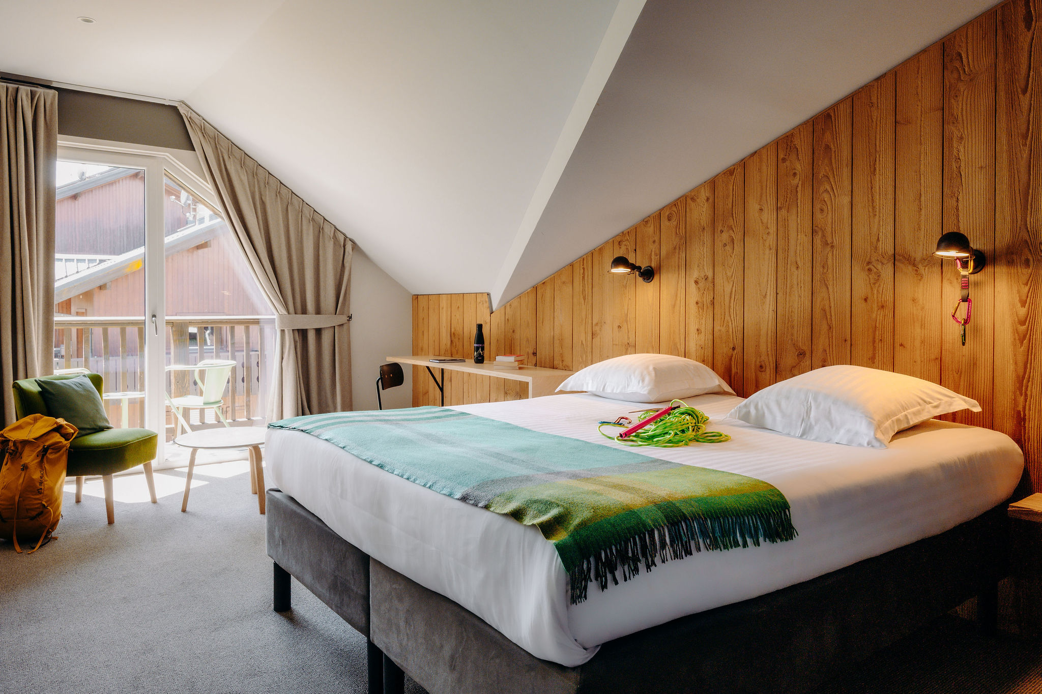 A second elegant bedroom with a large double bed, a relaxation area with a sofa and warm wood decor.