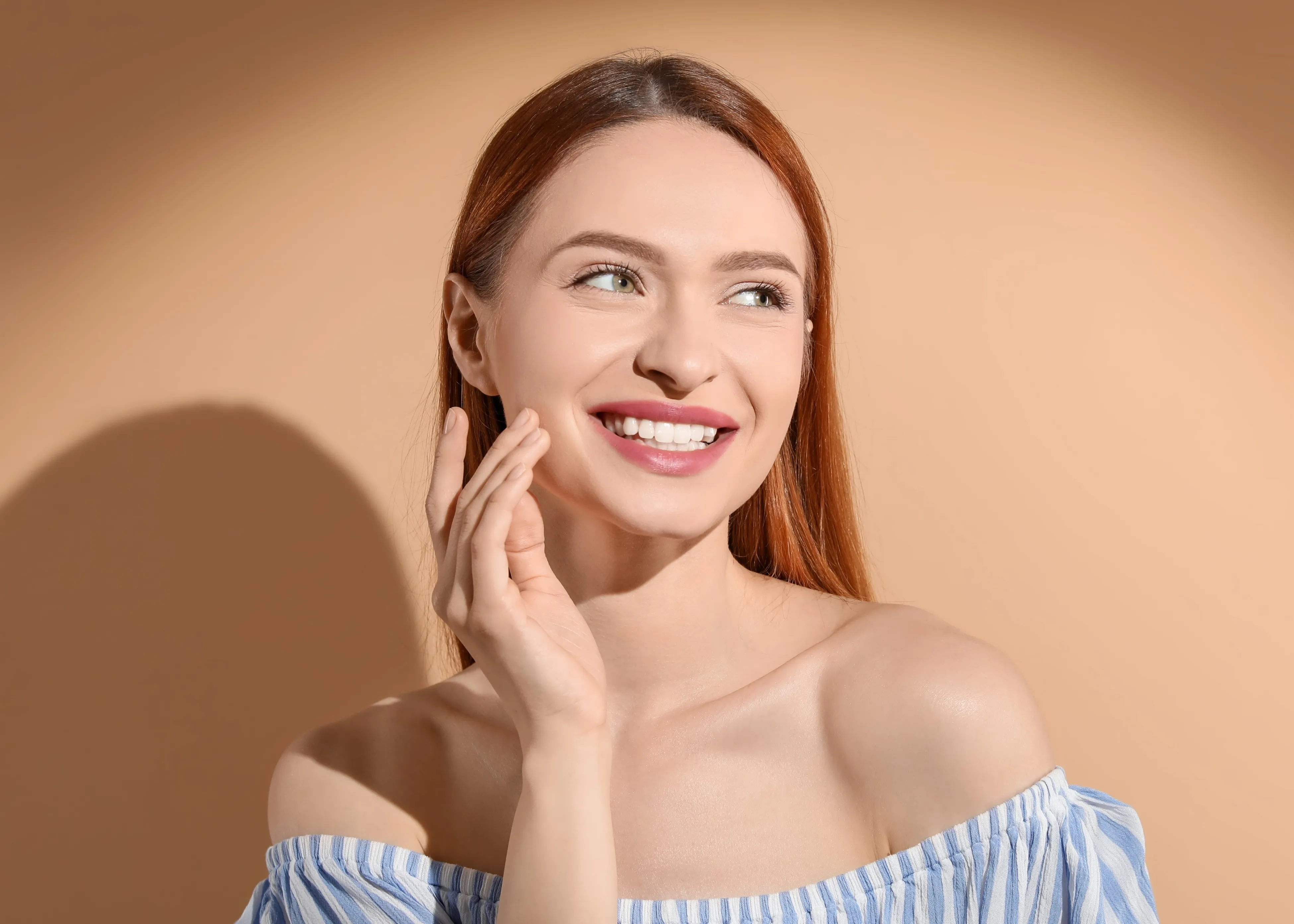 A woman smiling touching her cheek