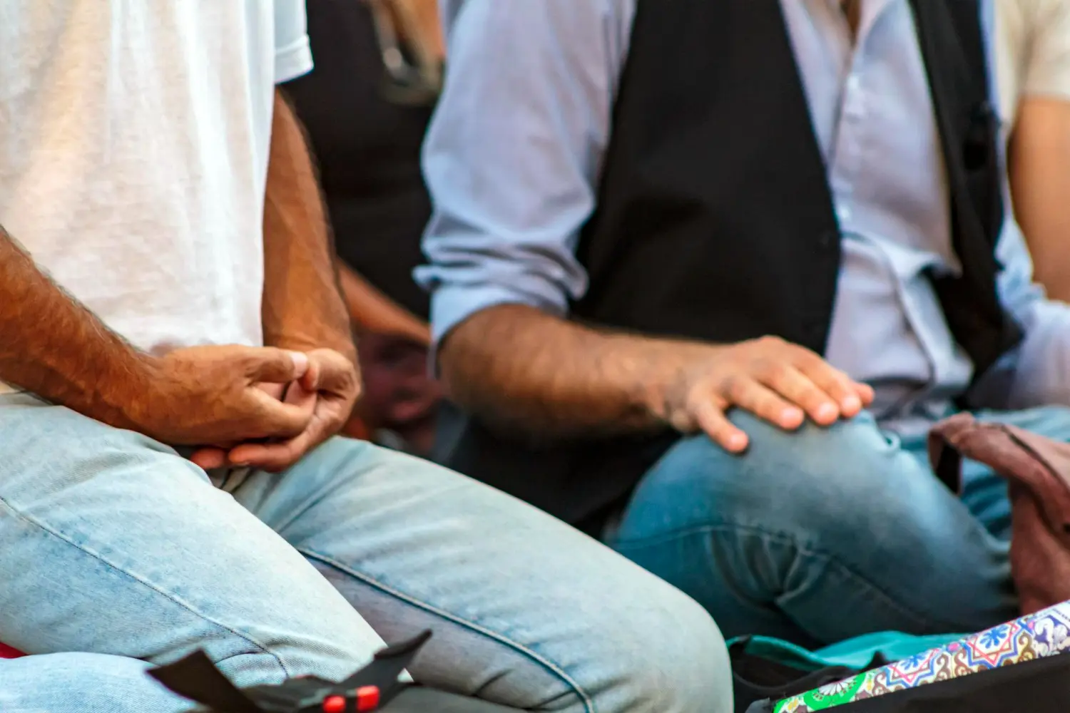 Close-up of people sitting together in a group circle, hands resting in a relaxed position—symbolizing openness, reflection, and participation in alumni engagement strategies.