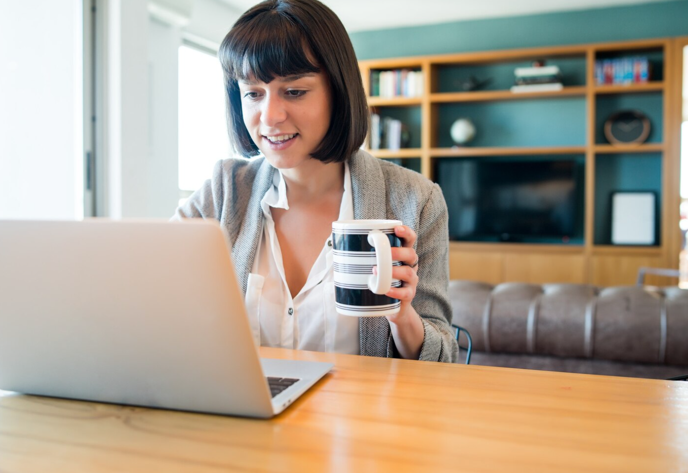 A woman seated at a table, working on a laptop and using tools dedicated to alumni management for treatment centers