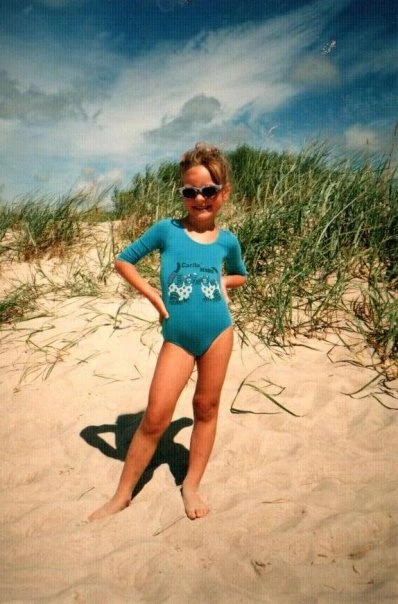 A full-length portrait of sassy, 5-year-old Magda smiling with sunglasses and weating blue swimming suit on the beach 
