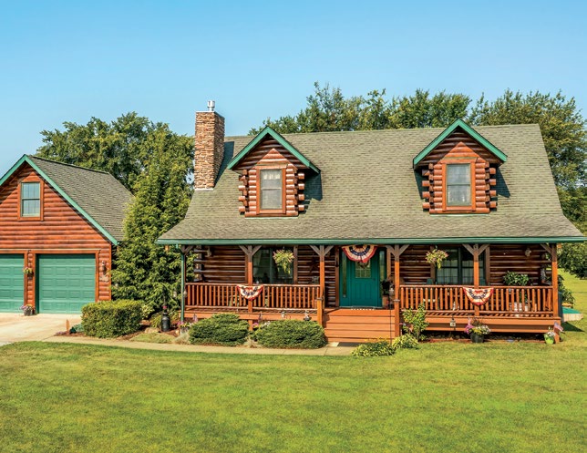 Kowatch custom log home in Loudonville, Ohio, with a full-length covered porch, dormer windows, and detached two-car garage.