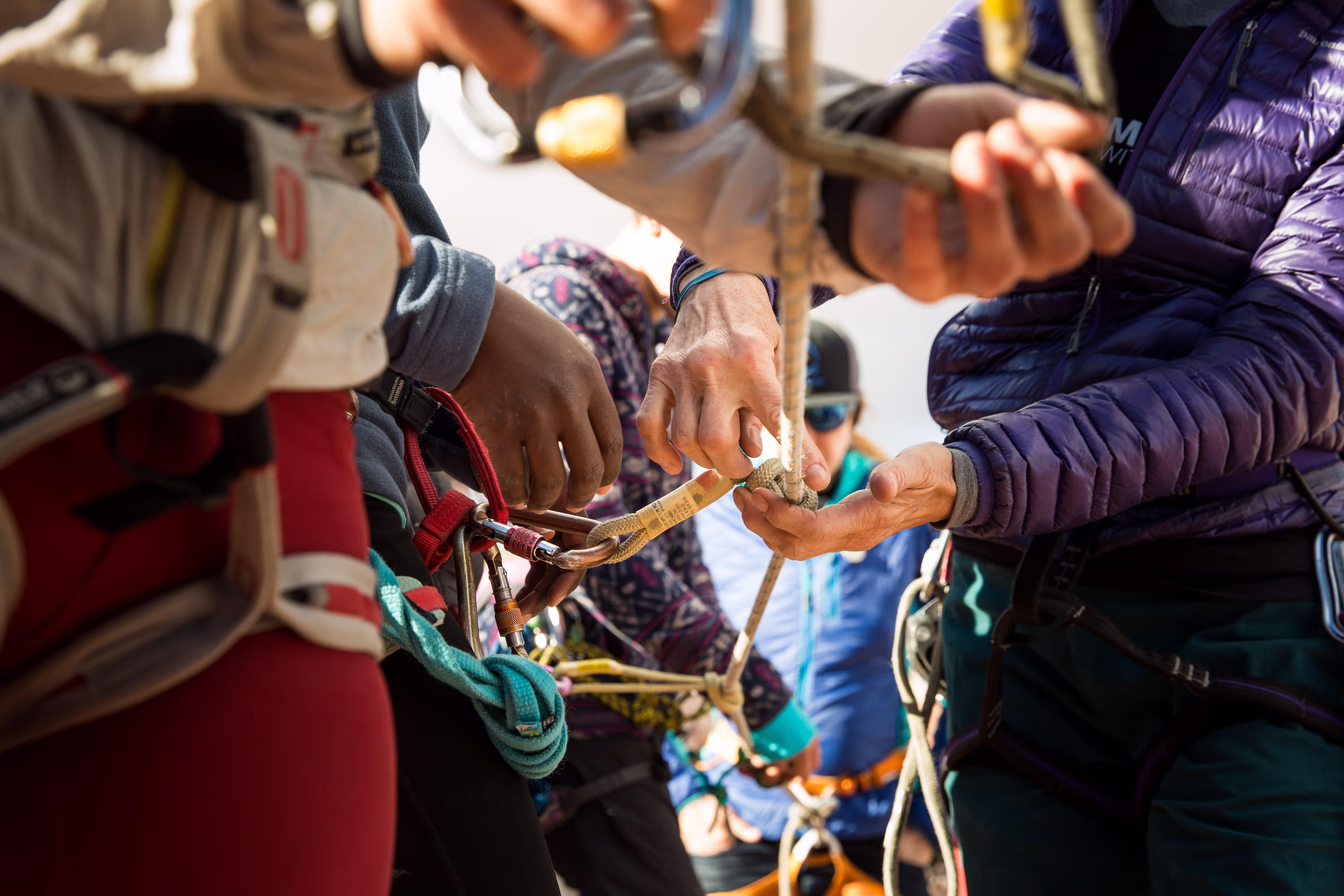 People securing climbing gear, focusing on hands attaching carabiners and ropes.