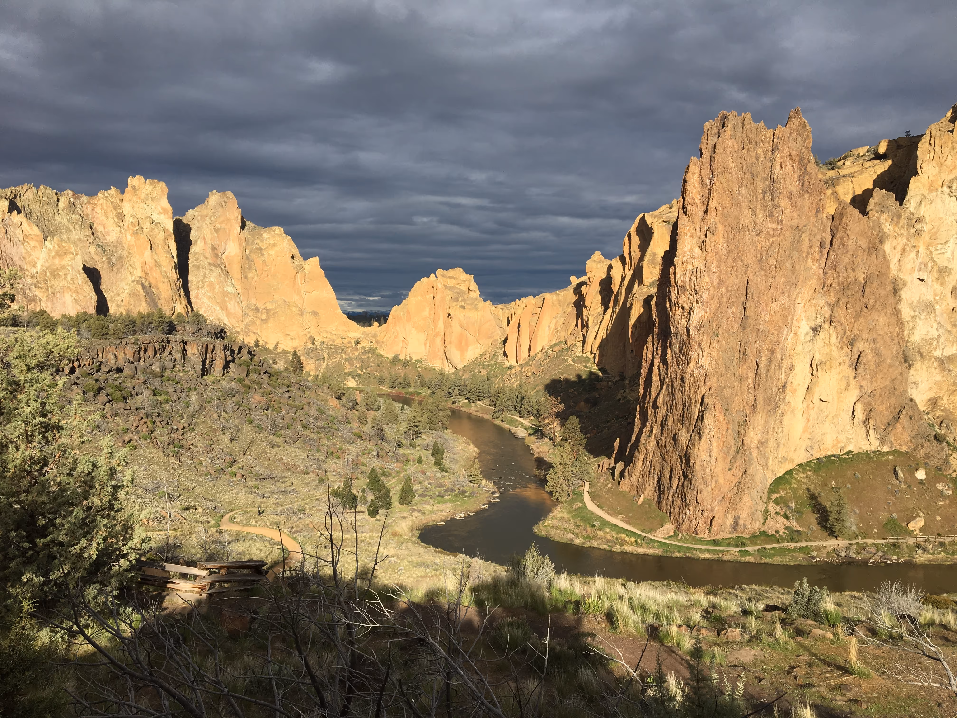 Rocky cliffs and a river under a cloudy sky.