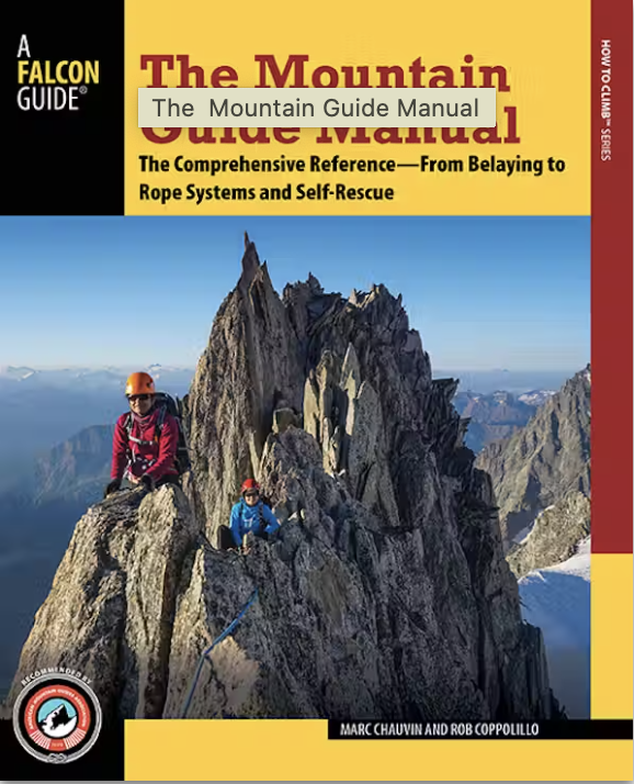 Two climbers wearing helmets ascend a rocky mountain peak with clear blue skies.