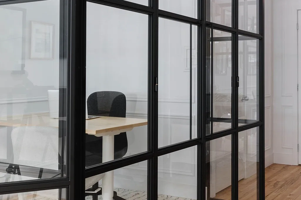 Cloison vitrée pour bureau à ossature noire dans un espace de travail lumineux
