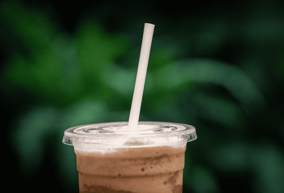 acercamiento de un vaso con una bebida cafe y un popote