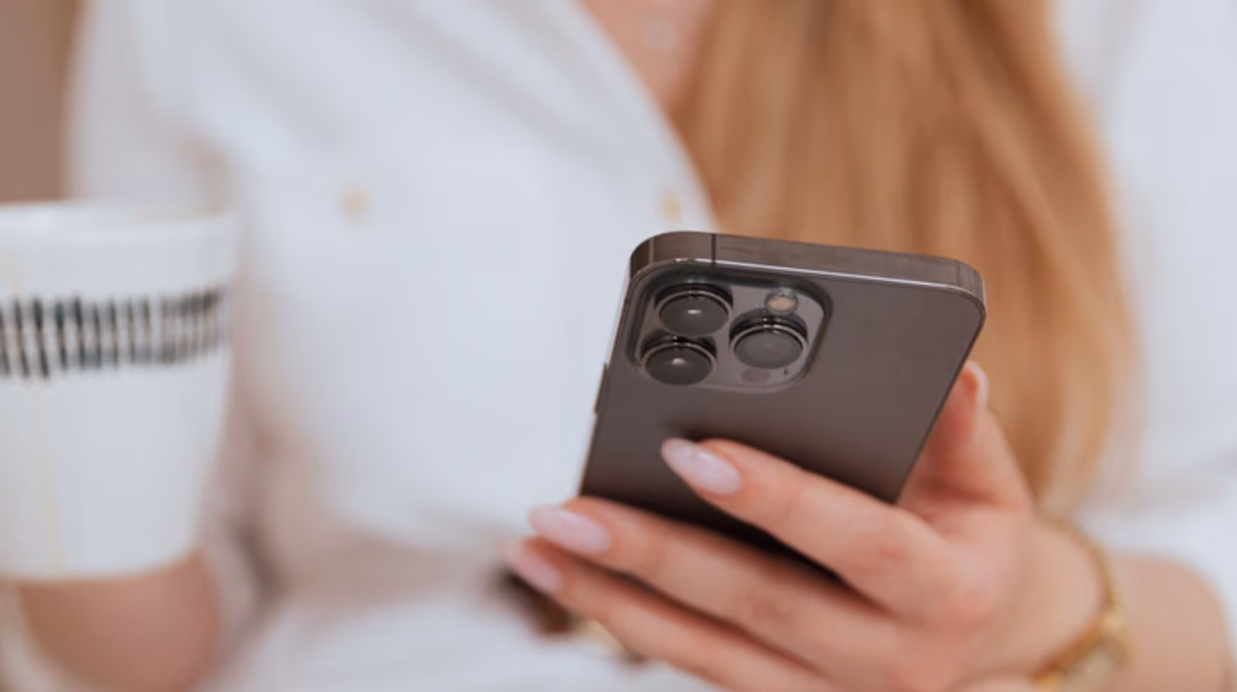 Close-up of hands holding smartphone reading email in bright, modern interior setting - authentic lifestyle photography for wellness brand marketing campaigns