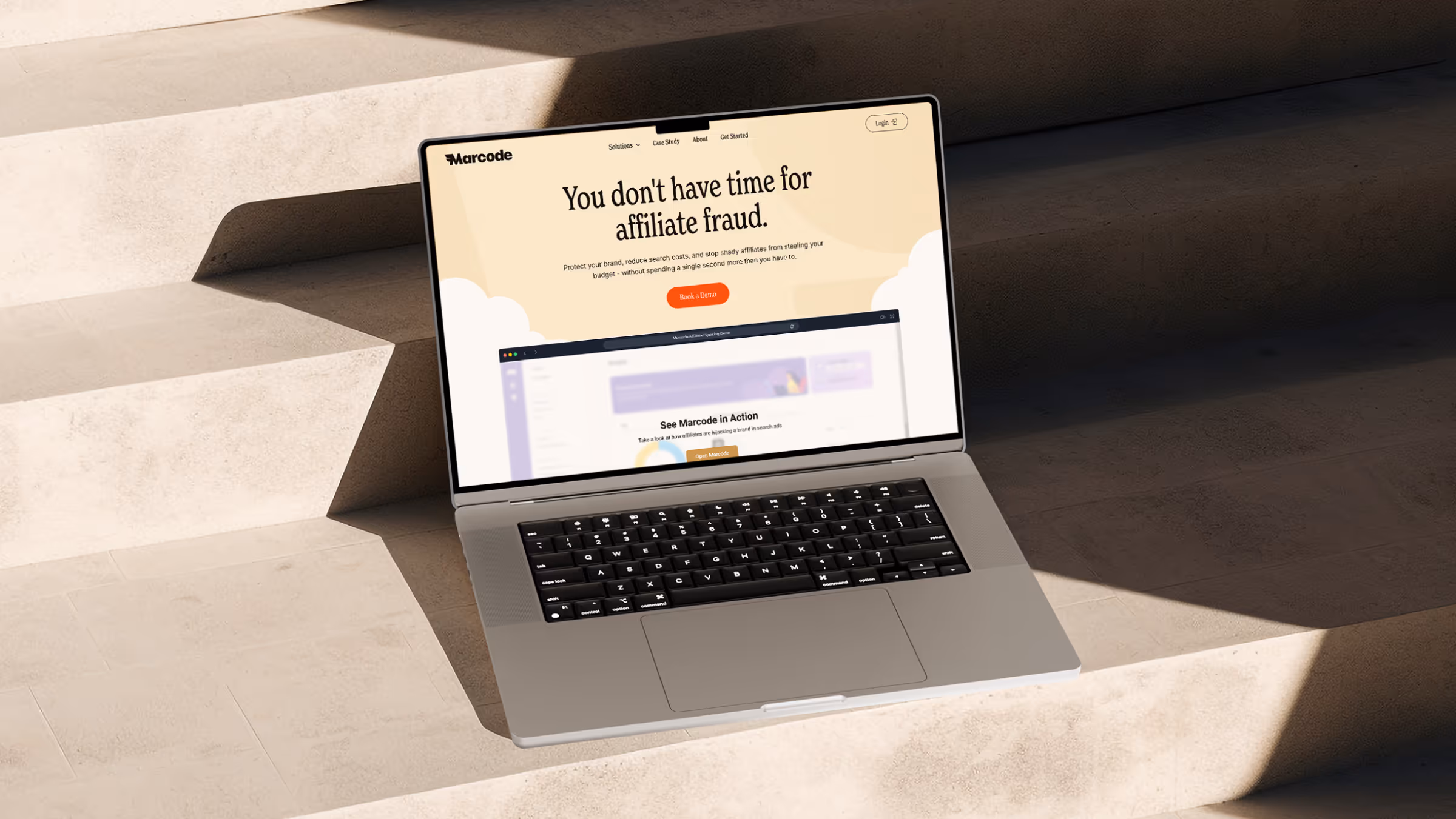 Open laptop on stone steps displaying Marcode website homepage about preventing affiliate fraud with options to book a demo.