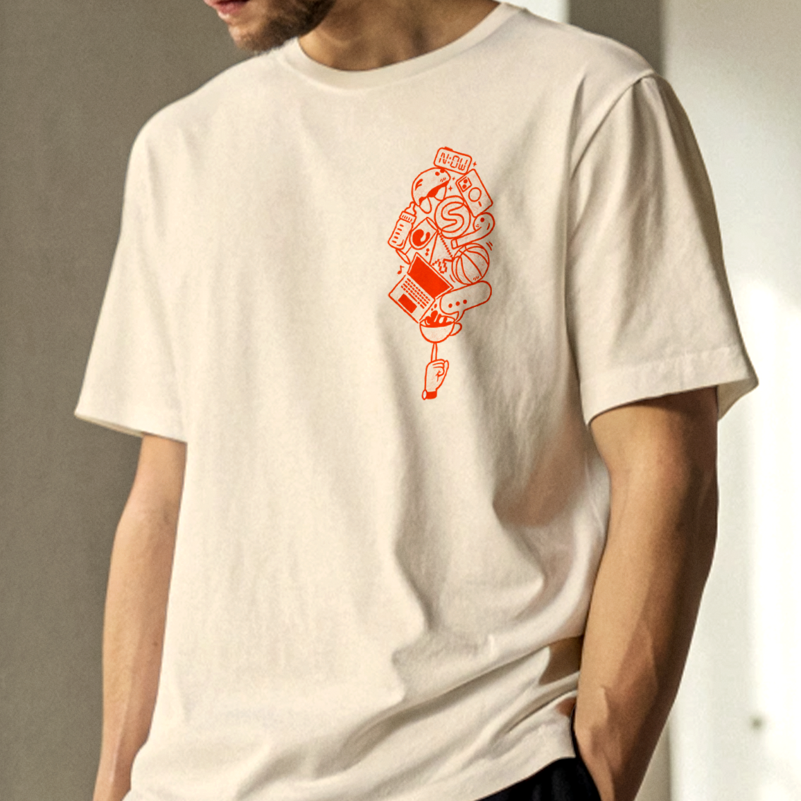Person wearing a white t-shirt with an orange graphic design of various objects including a bird, basketball, laptop, and coffee cup.