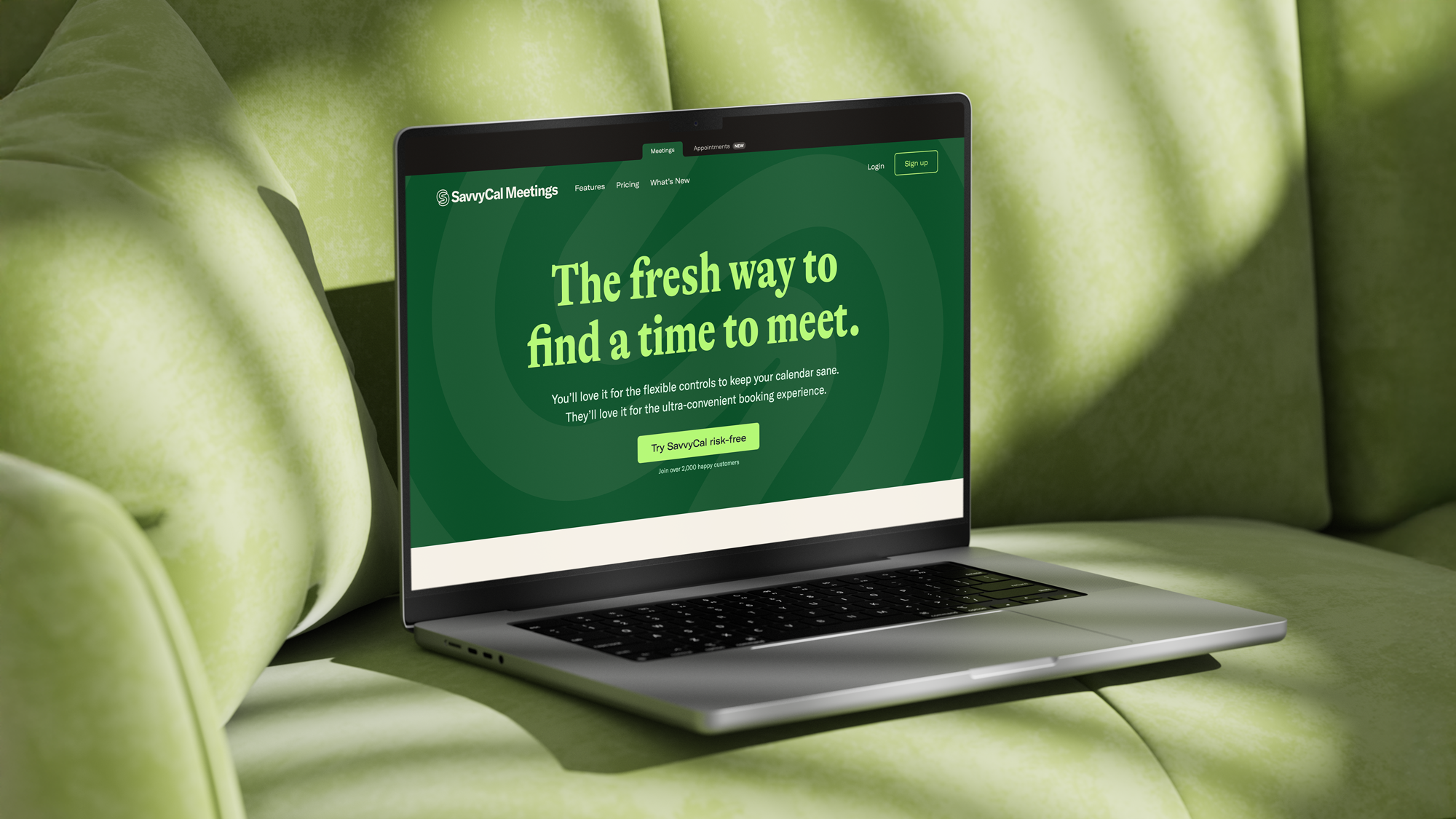 Open laptop on a light green couch displaying SavvyCal Meetings homepage with the slogan 'The fresh way to find a time to meet.'