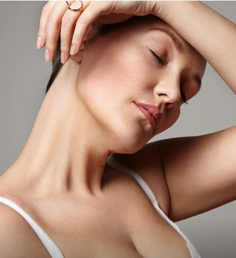 Close-up of a woman with closed eyes touching her forehead with her hand, showing smooth skin and a relaxed expression.