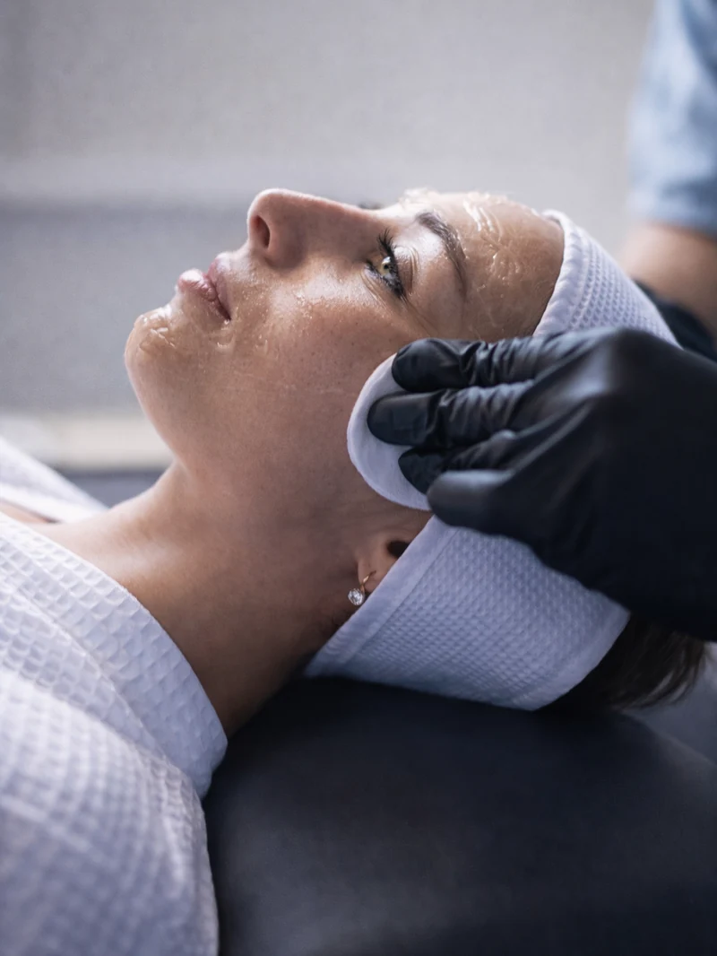 A client receiving a non-surgical facial treatment at SOM Aesthetics in Encinitas, showcasing a professional aesthetician preparing the skin for a minimally invasive cosmetic procedure