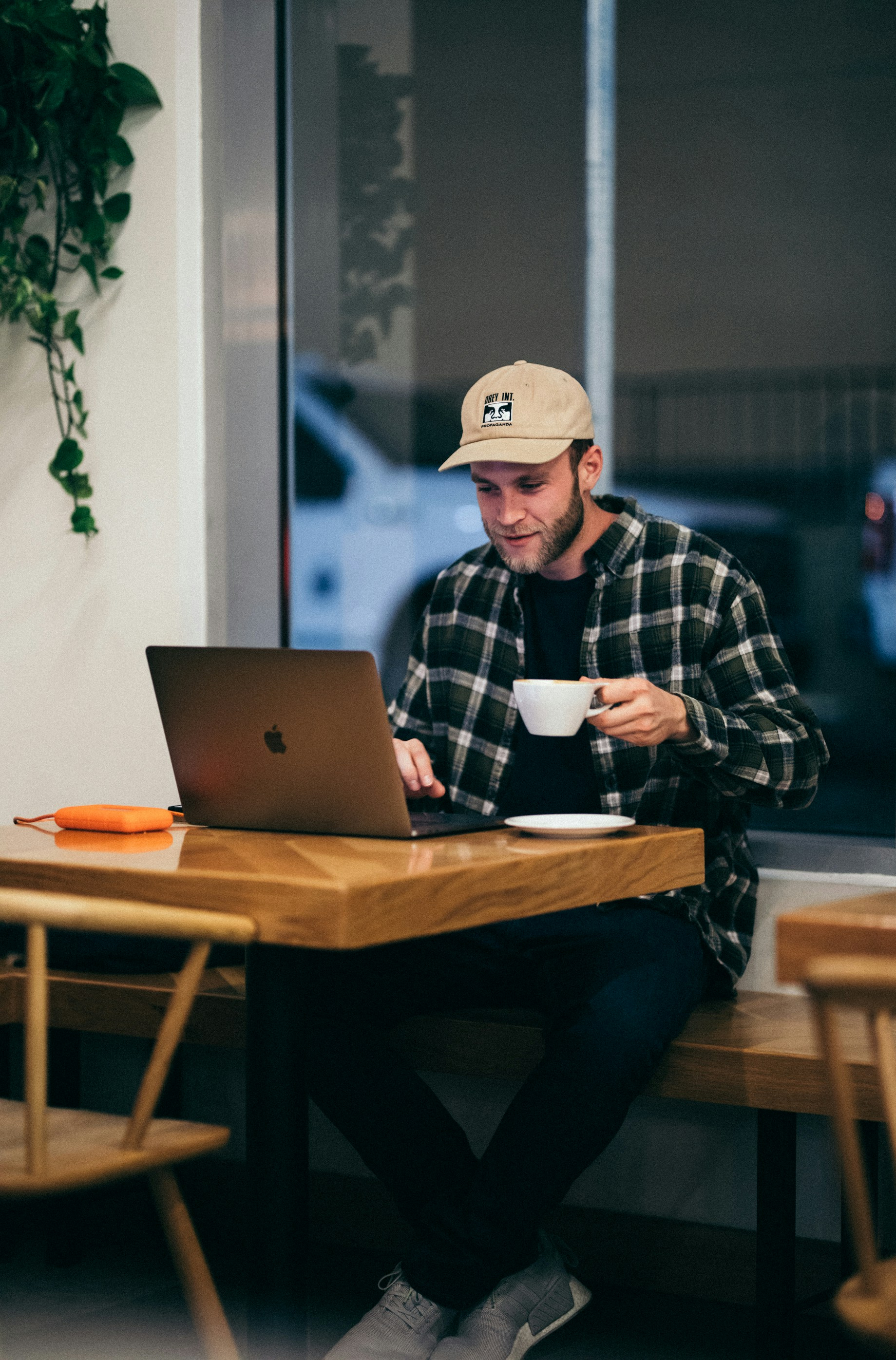A man sitting at a table with a laptop and a cup of coffee.