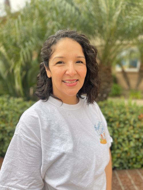A woman smiling in front of greenery
