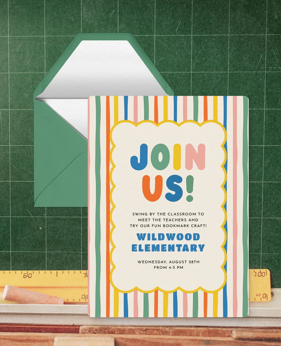 A colorful invitation card with vertical stripes in green, orange, yellow, blue, and pink and a scalloped white center that reads: Join Us! Swing by the classroom to meet the teachers and try our fun bookmark craft! Wildwood Elementary. Wednesday, August 28th from 4-5 PM. The card is placed in front of a green envelope on a green chalkboard background with a yellow ruler and chalk at the bottom.