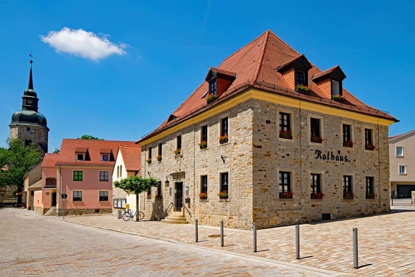 Sandstein-Rathaus mit roten Dachziegeln an einem sonnigen Tag in Sachsen-Anhalt