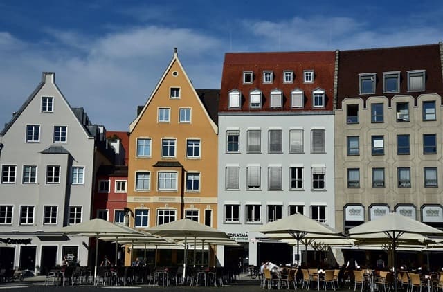 Bunte Giebelhäuser am Rathausplatz in Augsburg mit Straßencafés und historischer Atmosphäre.