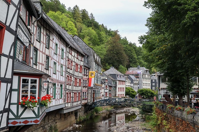 Historischer Stadtkern mit dicht aneinandergereihten Fachwerkhäusern entlang eines Flusslaufs.