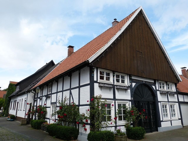 Das Bild zeigt eine Reihe gepflegter Fachwerkhäuser mit detailreichen Fassaden, weißen Gefachen und dunklen Holzbalken.