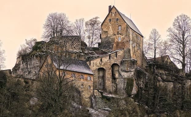 Historische Burganlage auf einem Felsen in herbstlicher Umgebung