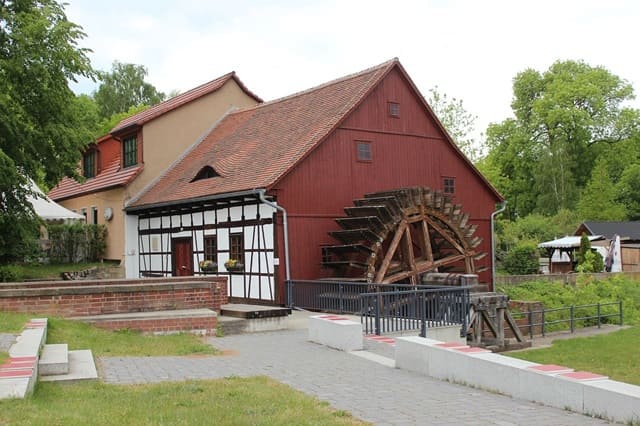 Historische Wassermühle mit Fachwerkbau und großem hölzernem Mühlrad.