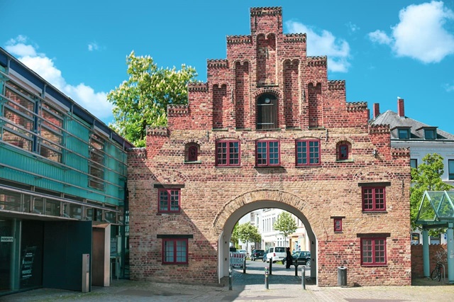 Stadttor aus Backstein mit gotischem Treppengiebel und rundem Durchgangsbogen.