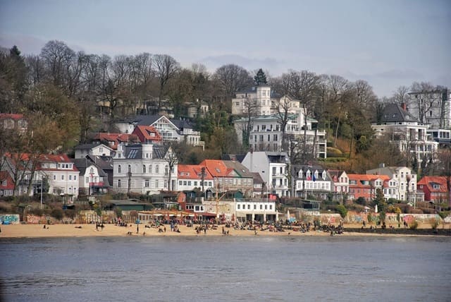 Dichte Hangbebauung mit teils denkmalgeschützten Villen, Kapitänshäusern und Altbauten direkt oberhalb des Elbstrands.