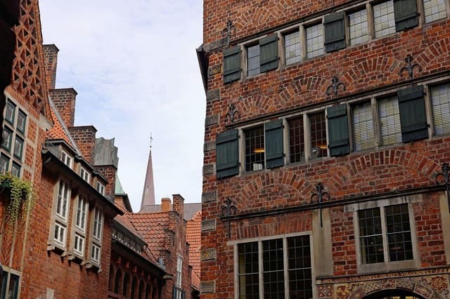 Markante Backsteinfassade eines historischen Gebäudes in der Bremer Böttcherstraße mit grünen Fensterläden und dekorativen Elementen.