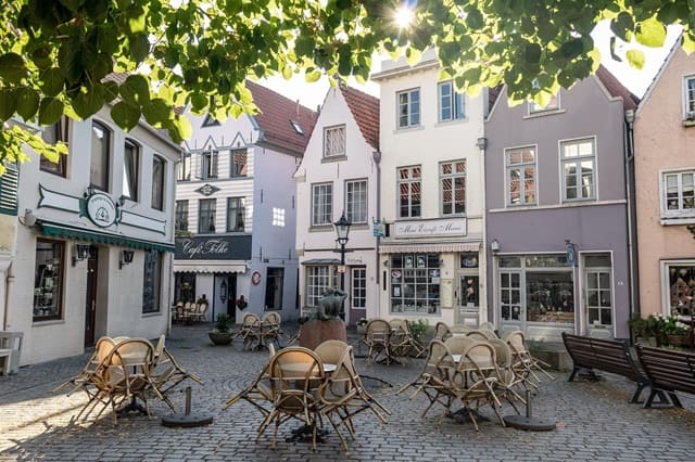 Platz im Bremer Schnoorviertel, umgeben von schmalen, denkmalgeschützten Häusern mit Gastronomie und Läden im Erdgeschoss.