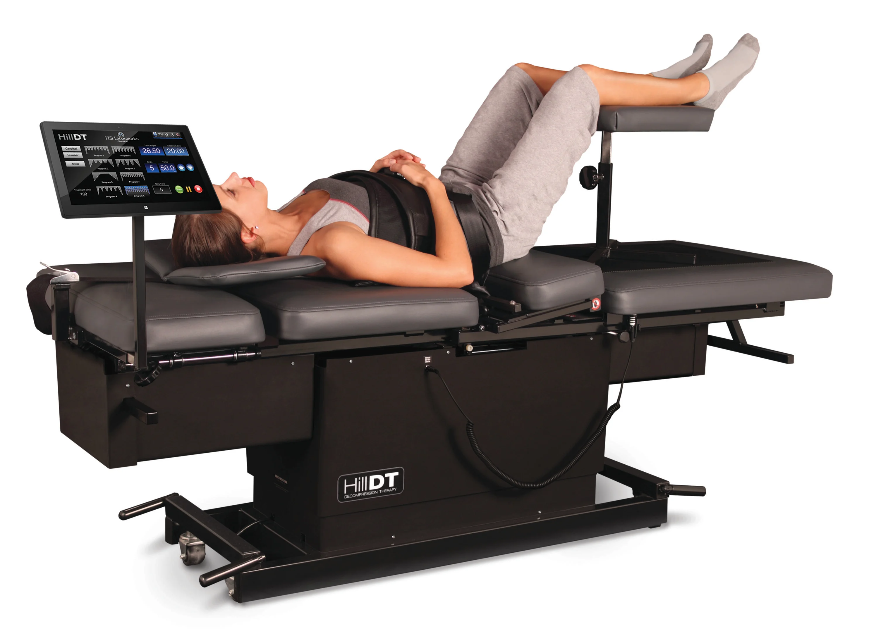 Woman lying on a HillDT decompression therapy table with legs elevated and controller screen visible.