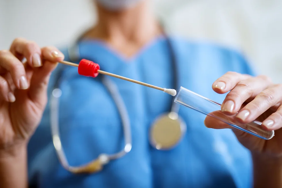 Medical professional in blue scrubs holding a swab and test tube for sample collection.