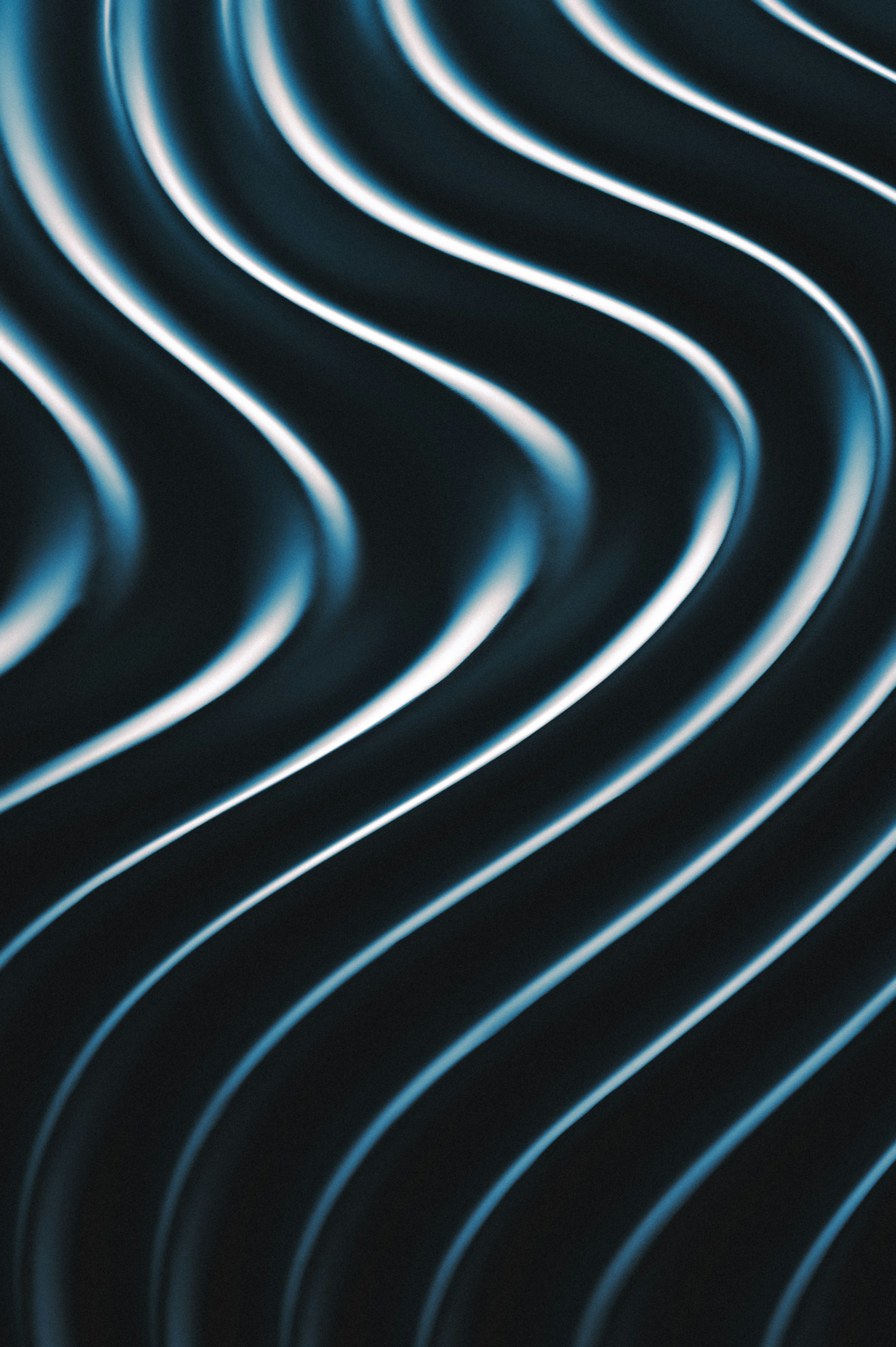 Close-up abstract image of smooth, dark wavy lines with blue and white highlights.
