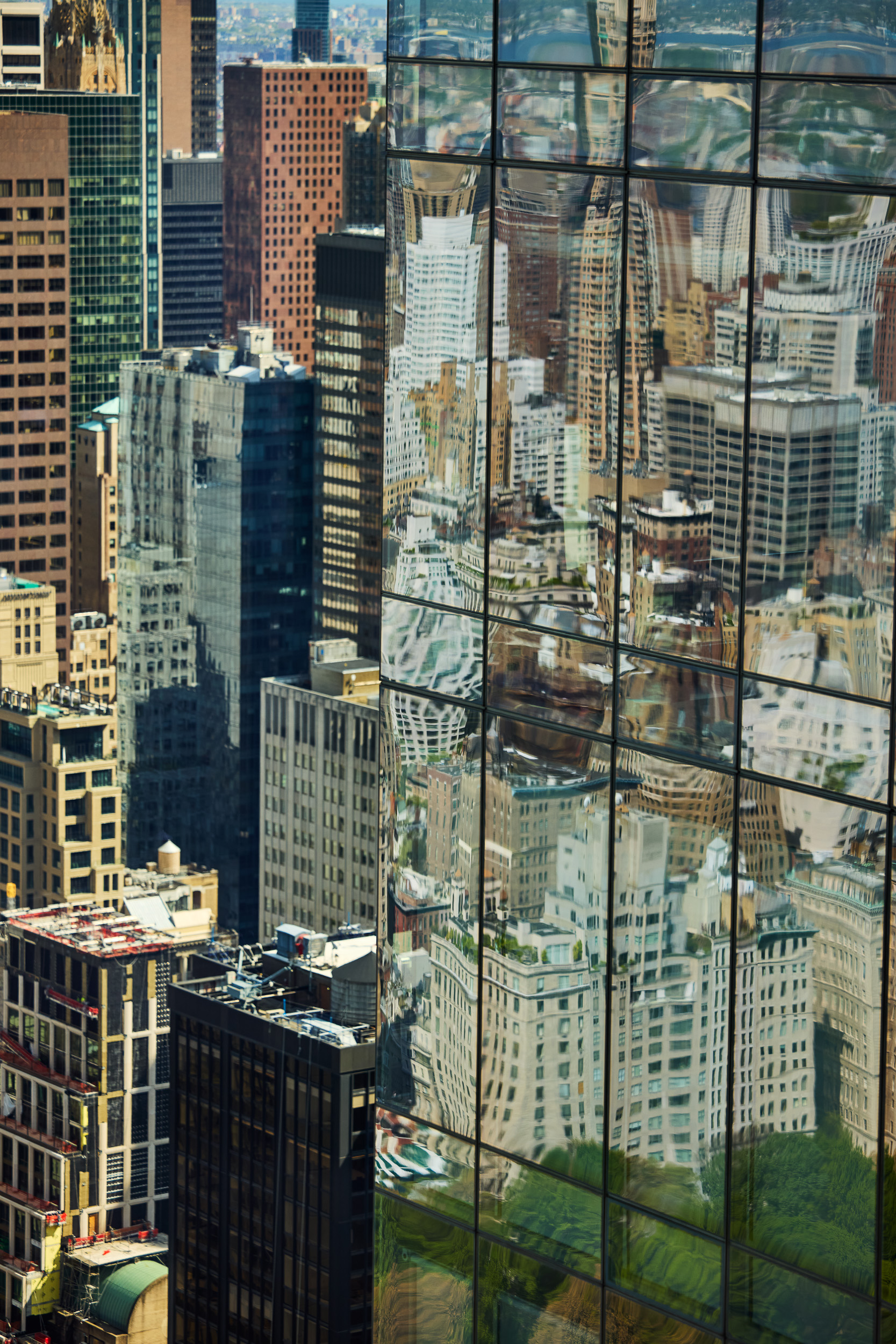 Reflection of a city skyline with various tall buildings on the glass facade of a modern skyscraper.