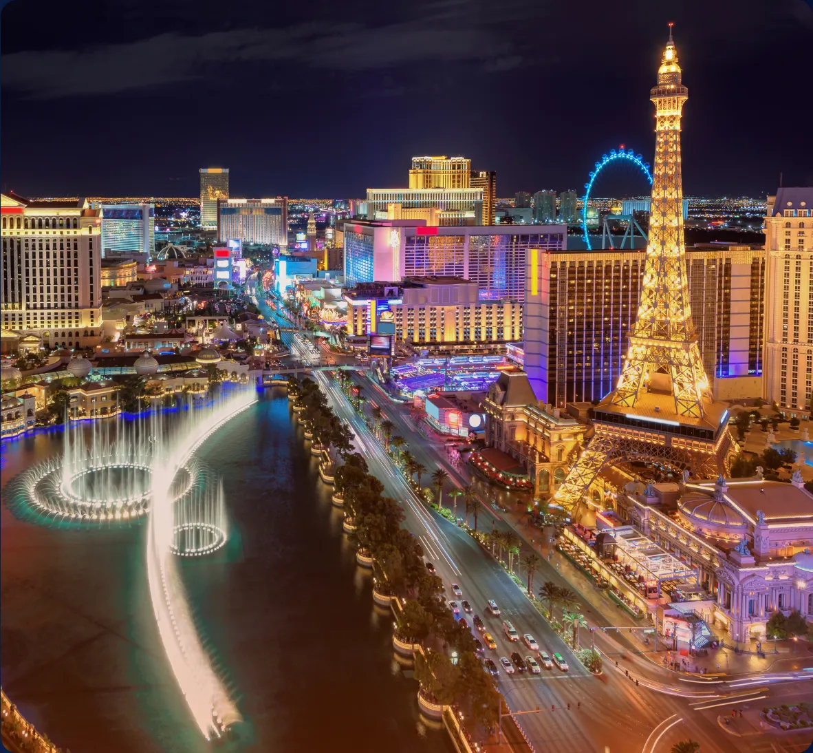 The las vegas strip at night with the eiffel tower in the background.