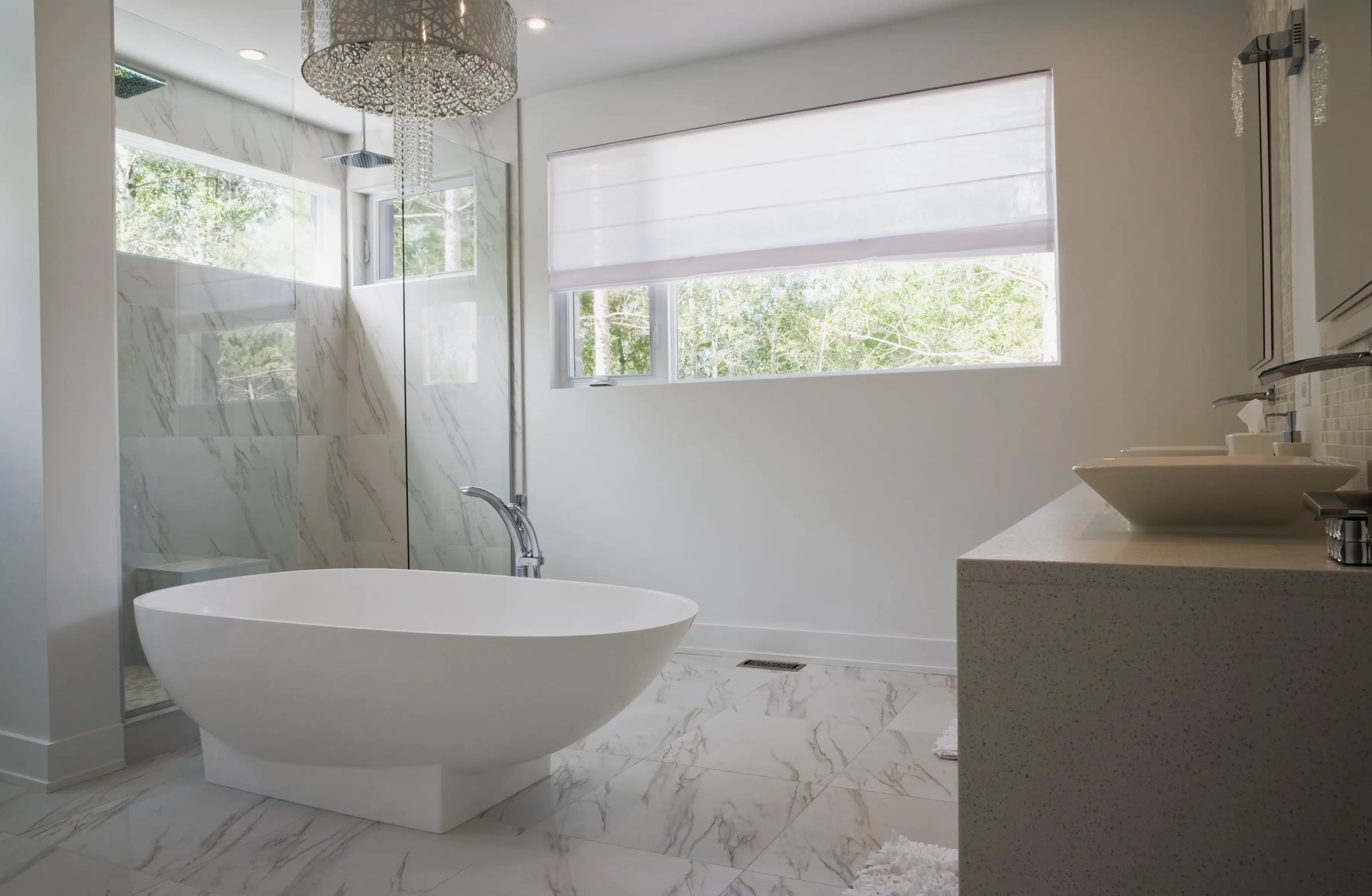 Modern bathroom remodel with freestanding tub, glass shower, marble tile flooring, and large windows