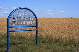 Welcome to Leduc County sign by a wheat field under a blue sky
