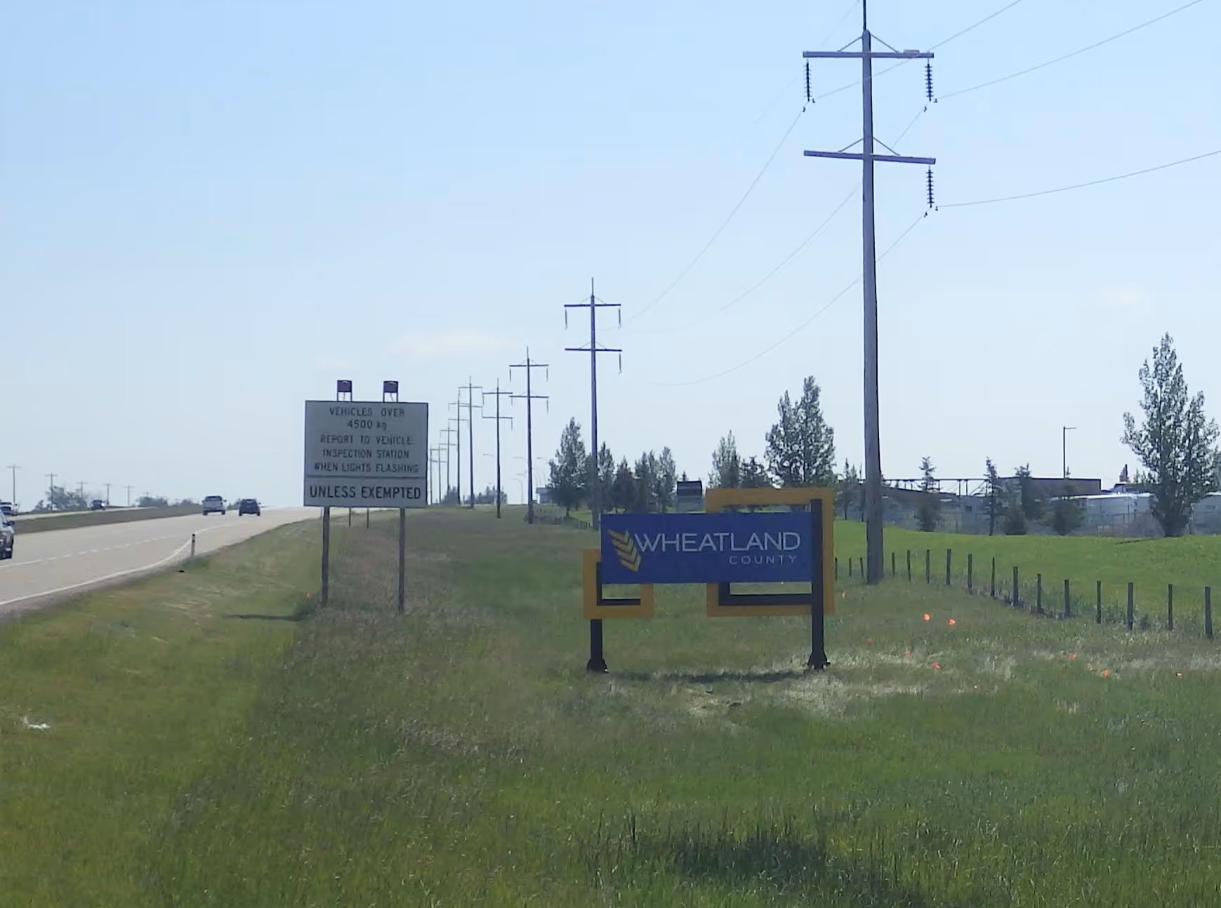 Wheatland County welcome sign beside a rural highway and power lines.